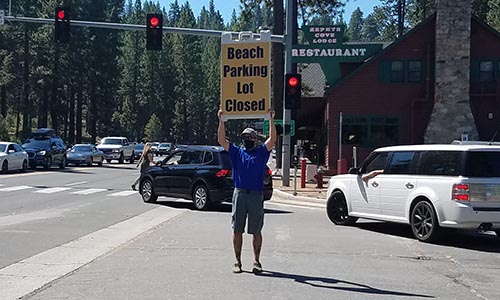 A man holding up a large sign saying a parking lot is full
